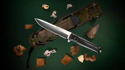 Tactical hunting knife with scabbard, black handle on a green background with decorative elements
