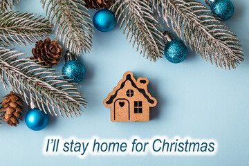 Text I’ll stay home for Christmas. Christmas wooden toy House on blue Christmas background. Concept staying at home. Covid