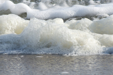 Sea foam on a sand tropical beach closeup. Travel and tourism, bubbles and macro waves. Selective focus.