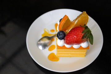 Top view of slice of orange fruit cake topped with a strawberry and a blue berry