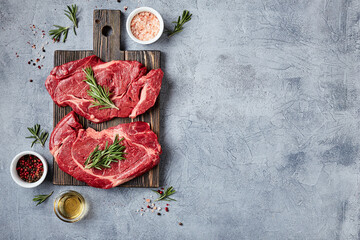 Two Fresh Raw meat Prime Black Angus Beef Steaks, Rib Eye, Denver, on wooden cutting board. Top view, place for text.