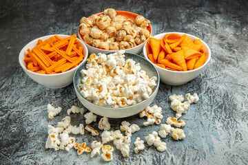 front view different snacks for movie time on light-dark background cips rusk popcorn