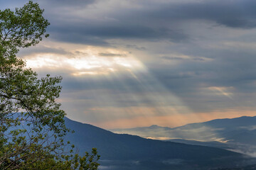 Dramatic cloudy sky with sun rays falling on mountains