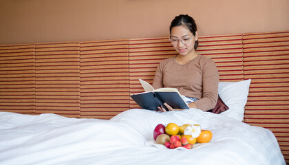 Asian young women reading books happy with fruit snacks in luxury hotel rooms, vacations, and...