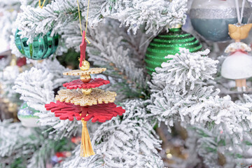 Multicolored snowflakes with gold beads on a snow-covered Christmas tree.