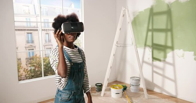 Portrait of African American young impressed excited woman stands in room wearing VR glasses and looking at new redesigned renewed apartment using modern innovations and virtual reality technology
