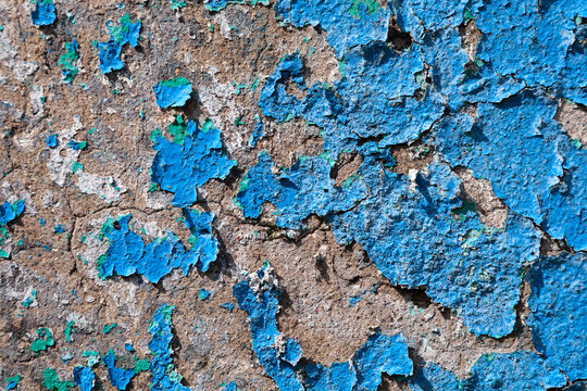 An old concrete wall with blue peeling paint. Texture of exfoliating paint from the wall. Empty space background
