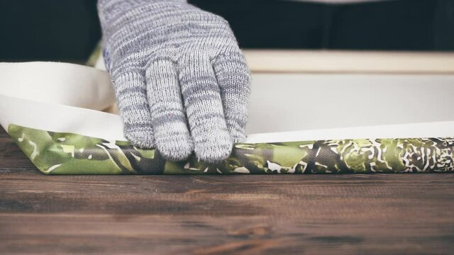 Man stretching the canvas on a stretcher. Printing photos on canvas.