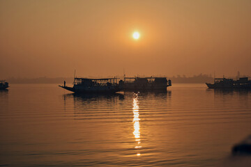 Fototapeta na wymiar Silhouette of motorboats against a backdrop of morning sun in Sunderbans delta, West Bengal