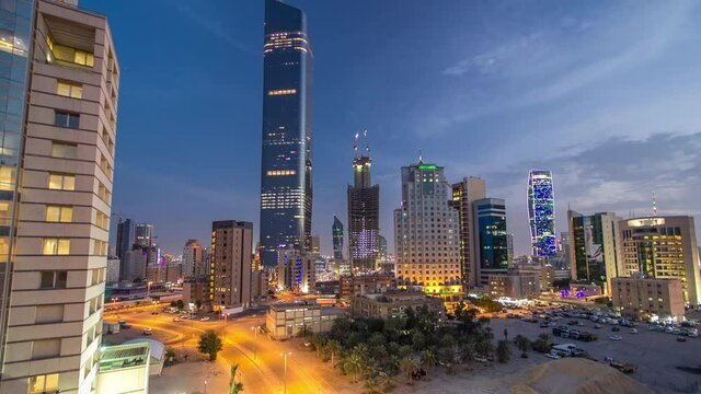 Kuwait City skyline with Skyscrapers day to night transition timelapse in downtown illuminated at dusk after sunset. Aerial view from rooftop. Middle East.