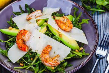 Fresh salad bowl with arugula, avocado, shrimps, parmesan cheese and pine nuts. Healthy food. Diet menu.