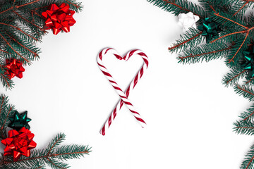Christmas white background with Christmas tree branches decorated with bows of red white and green color. Copy Space with New Year's candy cane.