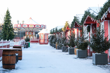 A long street with red Christmas houses, Christmas trees, a carousel. Winter Day. Without people. Christmas market
