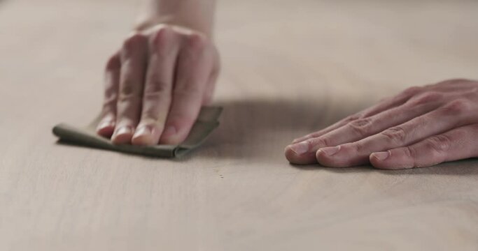 Slow motion slide orbit shot of man hand sanding black walnut wood table