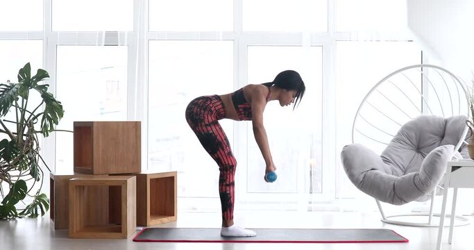 Strong fitness black woman doing arm workout with dumbbells in living room. Sport and fitness.