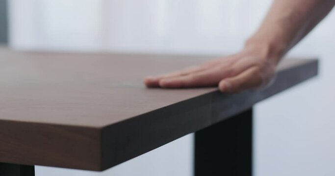 Slow motion of man hand checking toned walnut table surface before applying finish