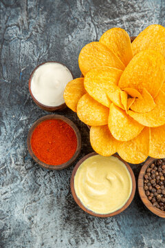 Vertical view of homemade potato chips decorated like flower shaped and different spices with mayonnaise on gray background stock image