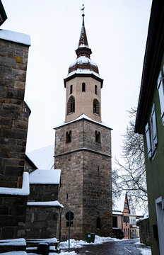 Old church spire and painted green building in the traditional Bavarian town of Feuchtwangen in Germany. Taken on a snowy winter day.