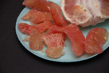 peeled slices of pink pomelo on a blue plate