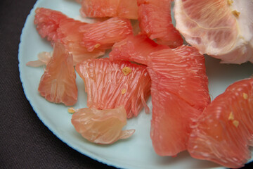 peeled slices of pink pomelo on a blue plate