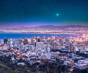 Cape Town city and harbour illuminated at night with blue sky stars