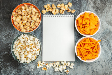 Obraz na płótnie Canvas top view different snacks popcorn rusks and cips on light floor snack movie cinema