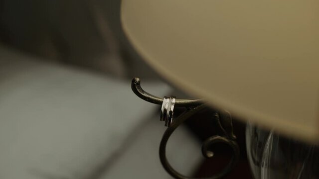 Gold wedding rings hang from vintage table lamp with lampshade