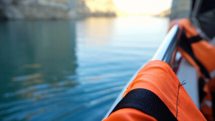 Contemporary motorboat with orange safety vests hanging on metal railing drifts on tranquil sea...