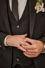 Groom in black tuxedo correct his wedding ring in white shirt. Wedding. Details