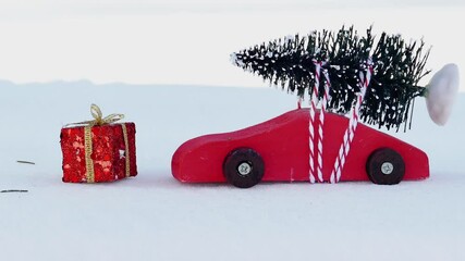 Hand is adding  gift next to red wooden toy car