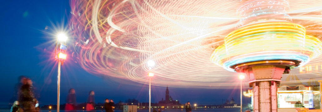 Karussell bei Nacht, bunte Lichter, Langzeitbelichtung, Menschen in Bewegung