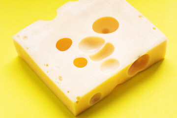 Swiss yellow cheese square chunks with holes on yellow background. Maasdam Dutch cow's milk cheese.