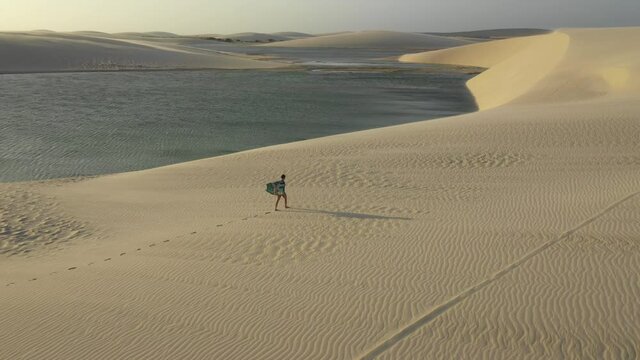 a pretty girl walking on sand dunes during sunset in Brazil