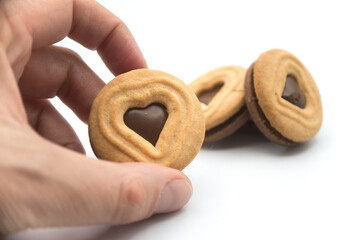 closeup of chocolate biscuits in shaped heart in hand on white background