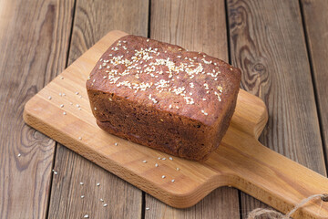Freshly baked sourdough bread made from rye flour on the kitchen board with sesame seeds.