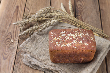 Freshly baked sourdough bread made from rye flour on a natural napkin with sesame seeds.