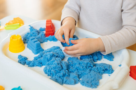 Close view of child's hands playing with kinetic sand. Children's creative game for early development and fine motor skills.