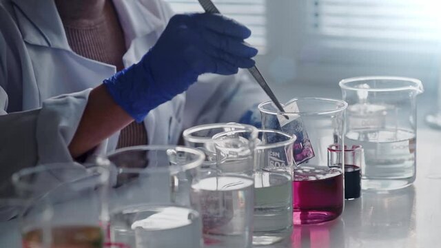 Laboratory worker scientist laboratory assistant tests chemicals for reactions in flask, interfering with different substances and obtaining a visual reaction. Concept of: Science, Chemistry, Covid-19