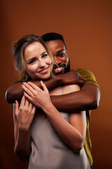 oung pretty couple diverse races together posing sensitive on brown background, lifestyle people concept
