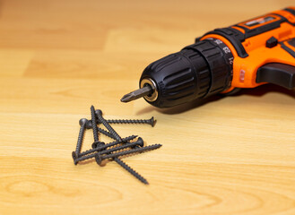 Cordless combi drill for used as normal drill, impact drill and screw driver. Cordless impact screwdriver and self-tapping screws for wood on white wooden background. Selective focus