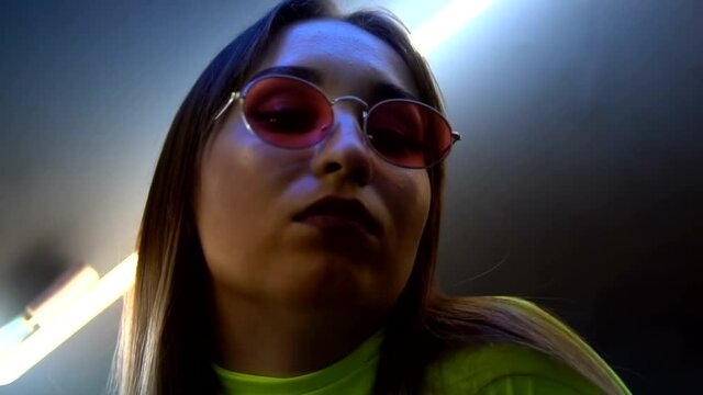 Fashionable girl on the background of a neon lapms clouse-up