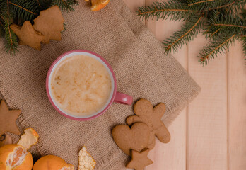 Flat lay Christmas, pink cup with coffee next to a branch of a christmas tree with tangerine and gingerbread on a wooden table, christmas table with coffee, happy new year time