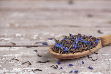 Loose Earl Grey tea leaves on a vintage wooden spoon and table with space for text