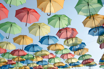 Plusieurs parapluies colorés suspendus sur ciel bleu - 400406704