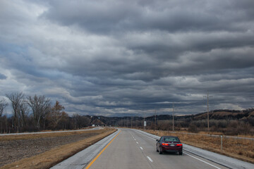 Fototapeta premium Beautiful dark blue sky over the highway. A landscape with a very unusual sky, trees without leaves and an asphalt road on an autumn day before a thunderstorm. Pacific Junction, IA, USA, 11-30-2019
