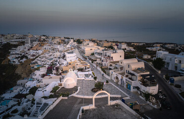 Oia town on Thira. Santorini island with colorful volcanic cliffs and deep blue sea aerial view