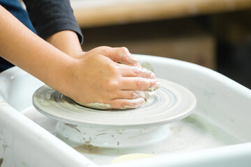 A boy sculpts a clay craft on a potter's wheel