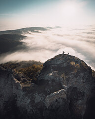 Dramatic Aerial view of Kojori fortressabove the clouds with person sillhouette and cross on top