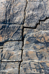 Stone texture and surface background. Cracked and weathered natural stone background. Geometric cracks. Perpendicular cross rocks cracks