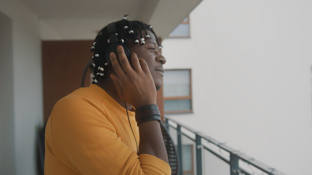 Portrait of african american black man with dreadlocks listening to the music on the balcony using headset. High quality photo